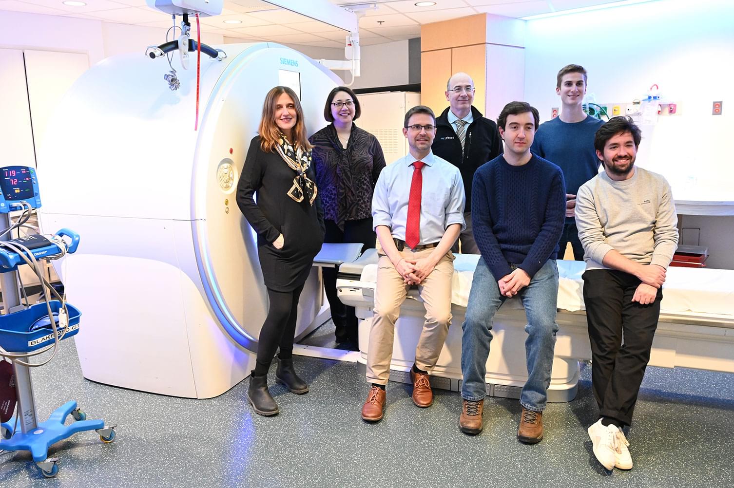 Sybil researchers pose for a photo in front of an CT scanner